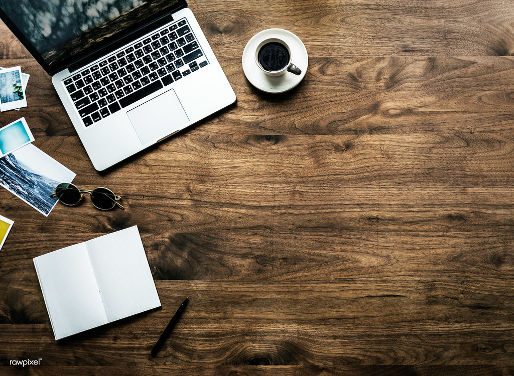 Laptop, notebook, and coffee on a wooden desk representing focused product planning